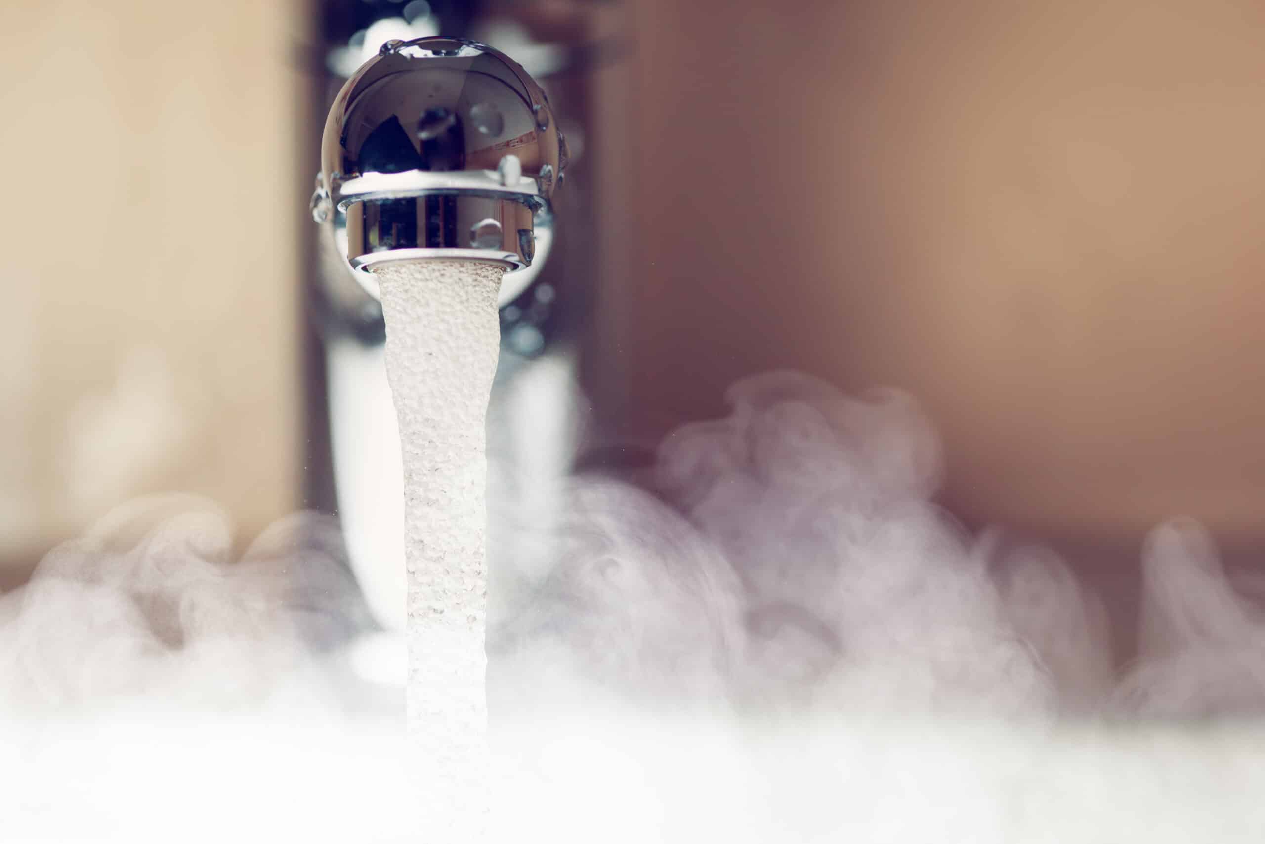 Water Flows From A Metal Faucet Into A Basin, Creating Steam.
