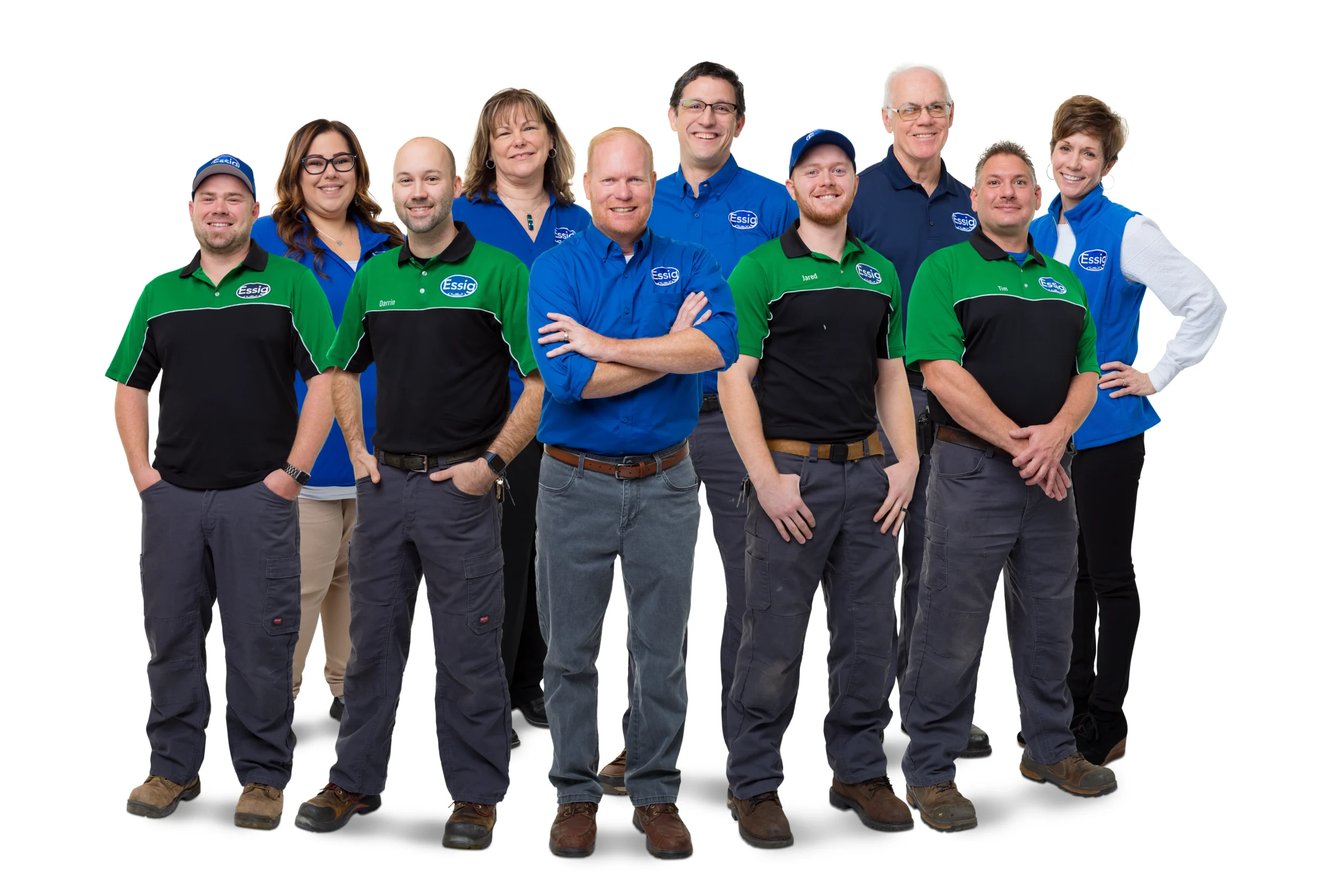 A Group Of Ten People, Featured On Our About Us Page, Some In Blue Shirts And Others In Black And Green Uniforms, Stand Together On A White Background, Facing The Camera And Smiling.