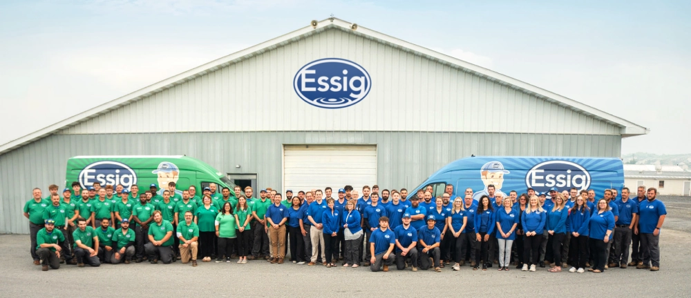 A Large Group Of People In Green And Blue Shirts Stand In Front Of A Building And Two Vans, All Branded With “Essig,” Highlighting The Team Spirit Behind Exciting Jobs And Rewarding Careers.